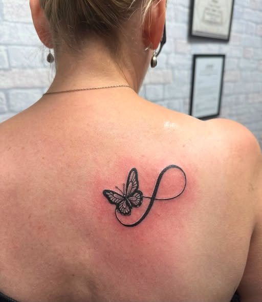 Infinity butterfly — Upper back · Fine line by Déjà Vu Tattoo, Bedworth